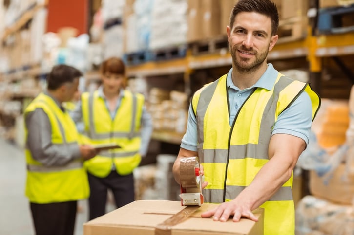 Smiling warehouse workers preparing a shipment in a large warehouse.jpeg