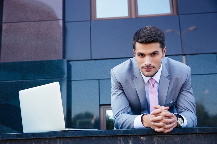 Portrait of a confident businessman with laptop computer outdoors. Looking at camera-1